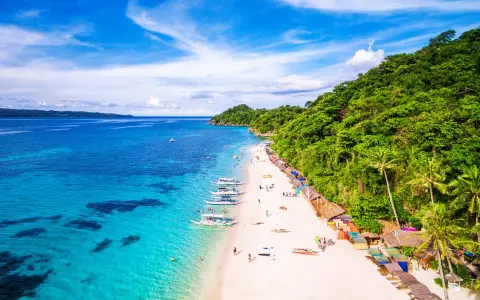 Piękna plaża na Filipinach w listopadzie. Turkusowa woda, biały piasek, palmy i łodzie. Idealna pogoda na wakacje.