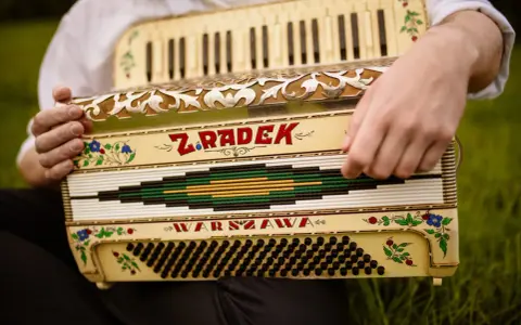 Dłonie grają na akordeonie "Z. Radek Warszawa", tworząc piękną harmonię.
