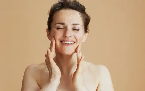 Kobieta z zamkniętymi oczami delikatnie masuje twarz peelingiem. Zastanawiasz się, ile razy w tygodniu robić peeling?
