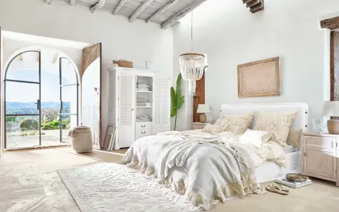 Elegantes dormitorio ideas con cama grande, armario blanco y puertas abiertas a un paisaje soleado.