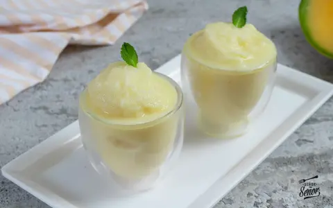 Dos copas de refrescante sorbete de melón, decoradas con hojas de menta, listas para disfrutar en un día caluroso.