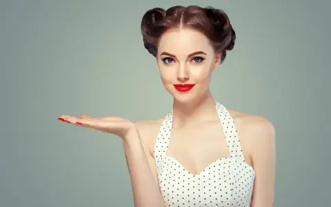 Uśmiechnięta pin-up girl w grochy, z burzą loków i czerwoną szminką, prezentuje coś na otwartej dłoni.