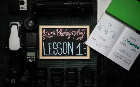 Zestaw sprzętu fotograficznego i notatnik z notatkami o ekspozycji, przysłonie i czasie naświetlania. Idealne materiały na kursy foto.