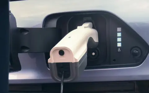 Cargando un coche eléctrico. Aunque los coches eléctricos no tienen embrague, este se conecta a la red para recargar su energía.