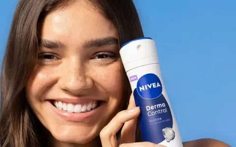 Donna sorridente con prodotto Nivea Derma Control, ideale per chi soffre di bruciore sotto le ascelle.