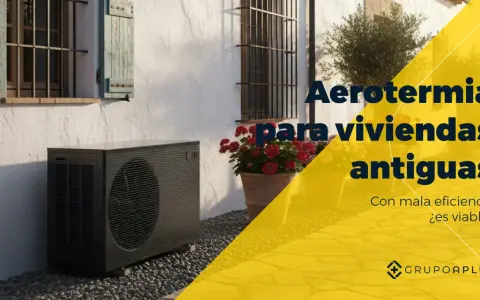 Unidad exterior de bomba de calor aire-agua junto a una casa antigua con flores. Aerotermia para viviendas antiguas.
