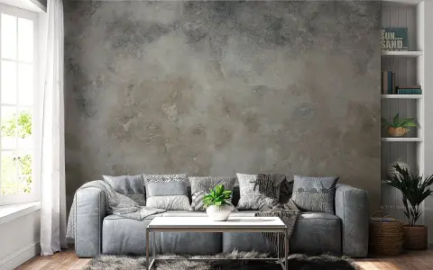 Sofá gris frente a una pared con efecto de pintar pared efecto envejecido. Alfombra peluda y mesa de centro metálica.