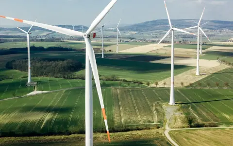 Weite Felder mit vielen weißen onshore Windkraftanlagen unter blauem Himmel.