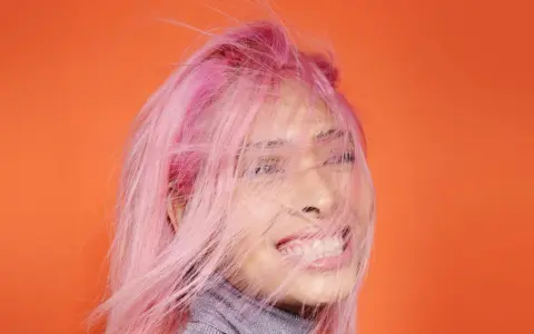 Frauenkopf mit pinken Haaren, die im Wind wehen. Ein Antistatik-Spray für Haare hätte hier Wunder gewirkt.