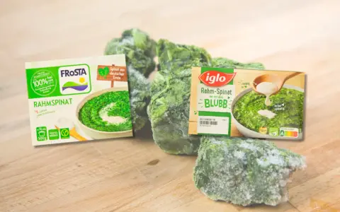 Gefrorener Rahmspinat von Frosta und Iglo, reich an Spinat Protein, liegt auf einem Holzbrett.