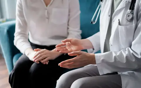 Lekarz omawia z pacjentem świadczenie rehabilitacyjne, gestykulując dłońmi.