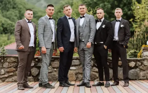 Sześciu mężczyzn w garniturach i białych koszulach, każdy z muszką. Różne kolory i wzory garniturów pokazują, jaka koszula do garnituru pasuje najlepiej.