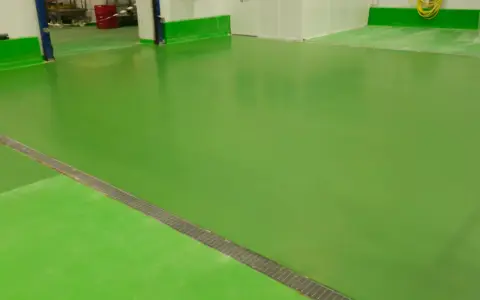 Un impecable pavimento industrial verde brillante, con una rejilla metálica a lo largo de una sección.