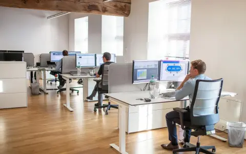 Bureau moderne avec employés travaillant sur des ordinateurs. Un homme utilise un service de bureau cloud pour gérer des données.