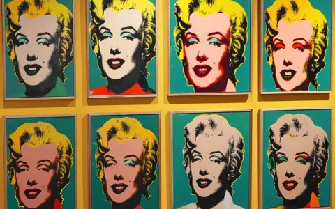 Osiem portretów Marilyn Monroe w stylu pop art Andy'ego Warhola, z różnymi kolorami tła i makijażu.
