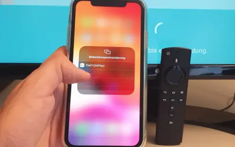 iPhone mit Fire TV Stick verbinden: AirPlay-Option wird auf dem iPhone angezeigt, daneben liegt die Fire TV Fernbedienung.