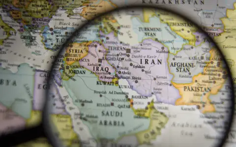 Mapa świata pod lupą, widoczne kraje Bliskiego Wschodu i Azji Południowej. W centrum Iran, Irak, Arabia Saudyjska.
