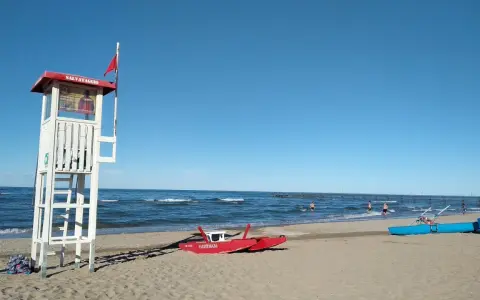 Torre di salvataggio e barchini sulla spiaggia di Rimini, pronti per nuove storie di mare.