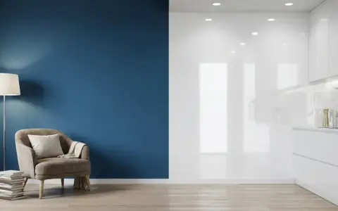 Un fauteuil confortable près d'un mur bleu mat, contrastant avec une cuisine blanche aux surfaces brillantes.