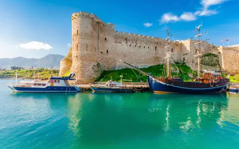 Zamek Kyrenia na Cyprze Północnym z łodziami przycumowanymi w turkusowej zatoce.