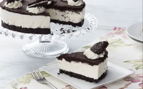 Una deliciosa tarta de oreo, con una base de galleta oscura y un cremoso relleno blanco, decorada con nata y galletas oreo.