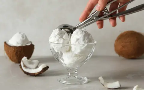 Copa de cremoso helado de coco, con trozos de coco fresco alrededor. ¡Un postre tropical!