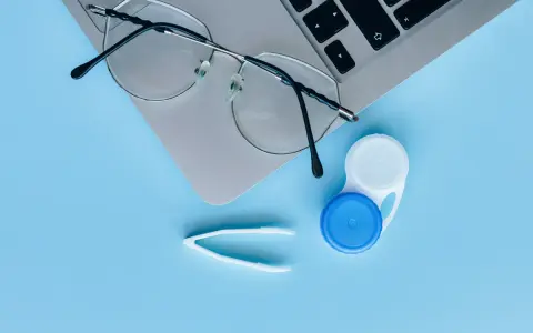 Okulary, pojemnik na soczewki i pęseta leżą obok laptopa. Czy można nosić soczewki i okulary jednocześnie?