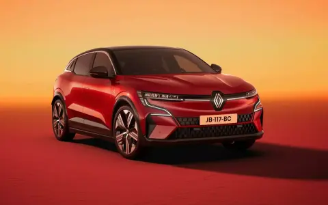 Nowy Renault Megane 5 w kolorze czerwonym, z czarnym dachem, prezentuje się dynamicznie na tle pomarańczowo-czerwonego gradientu.