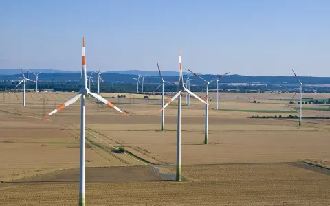 Großer onshore windpark in einer weiten Feldlandschaft unter blauem Himmel.