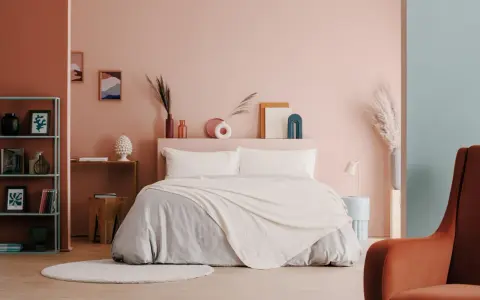 Camera da letto moderna con letto king-size, biancheria grigia e coperta color crema. Idee per come abbellire una camera da letto con decorazioni astratte e piante.