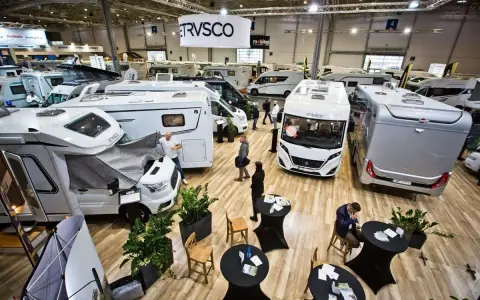 Wielka hala targowa pełna kamperów i przyczep kempingowych. Widać logo ERWIN HYMER GROUP.