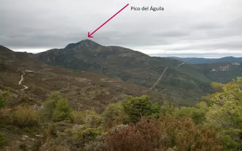 Un sendero serpentea hacia el **Pico del Águila**, coronado por antenas, bajo un cielo nublado.