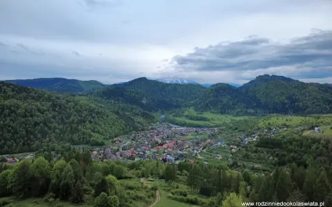 Widok na malowniczą dolinę z miasteczkiem Szczawnica. W oddali góry, a na pierwszym planie zielone wzgórza. To idealne miejsce na odkrywanie szczawnickich atrakcji.