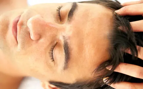 Fingers gently work through dark hair, demonstrating how to massage scalp for relaxation and hair health.