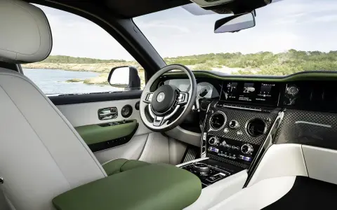 Wnętrze luksusowego Rolls-Royce SUV z zielonymi i białymi skórzanymi detalami, widok na morze.