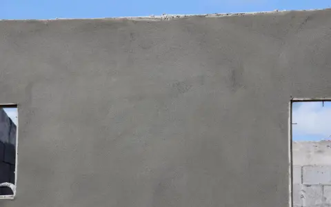 Le ragréage du mur extérieur est presque terminé, offrant une surface lisse et uniforme avant l'application de la finition.