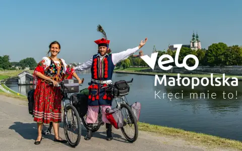 Para w strojach ludowych na rowerach nad Wisłą, promuje Velo Małopolska.