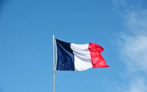 Die französische Flagge weht im Wind vor blauem Himmel. Ein Symbol für ein spannendes Auslandsjahr in Frankreich.