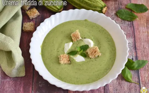 Crema fredda di zucchine servita in una ciotola bianca, guarnita con crostini, panna e menta. Fresca e invitante.