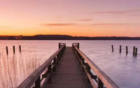 Holzsteg am See bei Sonnenuntergang, ein idyllischer Ort für Badeseen Schleswig-Holstein.