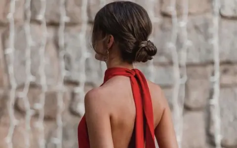 Elegante moño bajo en una mujer con vestido rojo, luciendo su espalda descubierta y un pendiente llamativo.