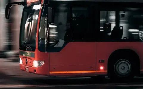 Czerwony autobus w ruchu miejskim, widok z przodu i z boku.