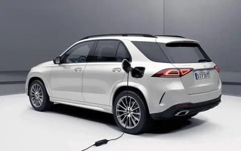 Biały samochód hybrydowy Mercedes-Benz GLE jest ładowany.