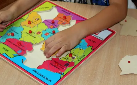 Dziecko układa puzzle z mapą Polski, ucząc się regionów. To świetne gry dydaktyczne w przedszkolu.