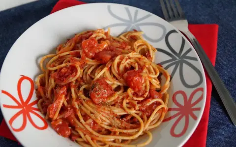 Pyszne spaghetti napoli przepis na talerzu, z sosem pomidorowym i ziołami. Idealne danie dla miłośników włoskiej kuchni.