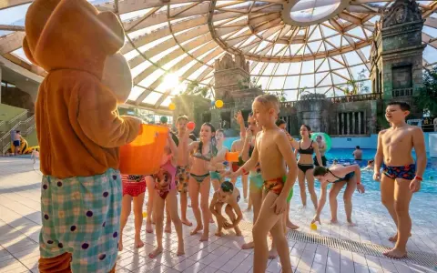 Maskotka rzuca piłeczki dzieciom w aquaparku w Budapeszcie. Radosna zabawa pod szklaną kopułą.