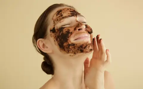 Mujer disfrutando de una mascarilla de café para la cara, con los ojos cerrados y una sonrisa.