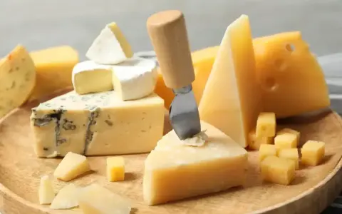Deska serów: pleśniowy, camembert i twarde sery, w tym ser sałatkowy pokrojony w kostkę.