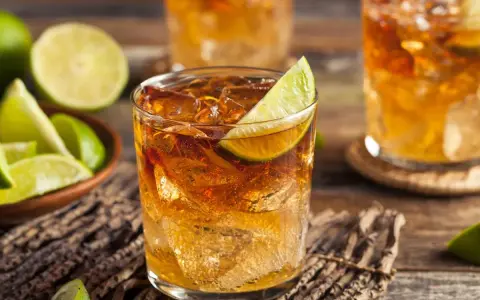 Idealny drink z rumem: orzeźwiający rum z lodem i limonką, obok miseczka z ćwiartkami limonki.