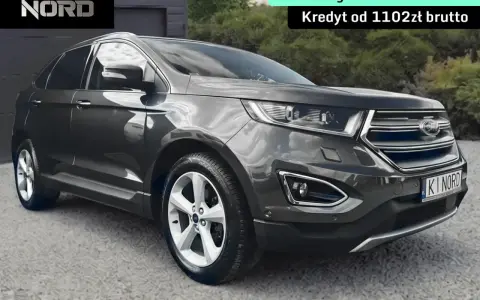 Ford Edge 2.0 TDCI w ciemnoszarym kolorze, zaparkowany przed garażem. Oferta leasingu i kredytu.